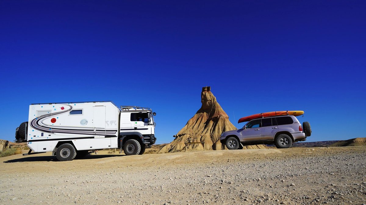 Camion aménagé et 4x4 devant une cheminée de fée des Bardenas