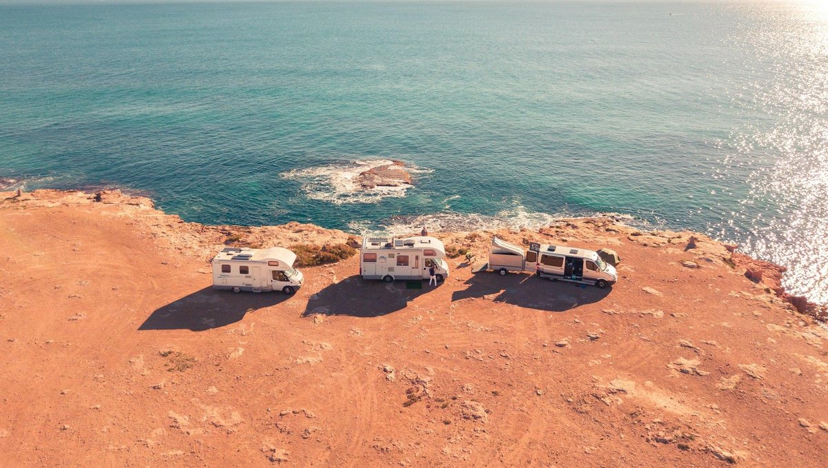 Trois camping-cars au bord d'une falaise face à la mer